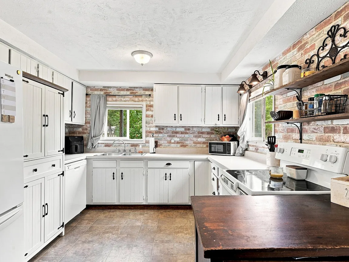 Bright kitchen with white cabinets and exposed brick accents