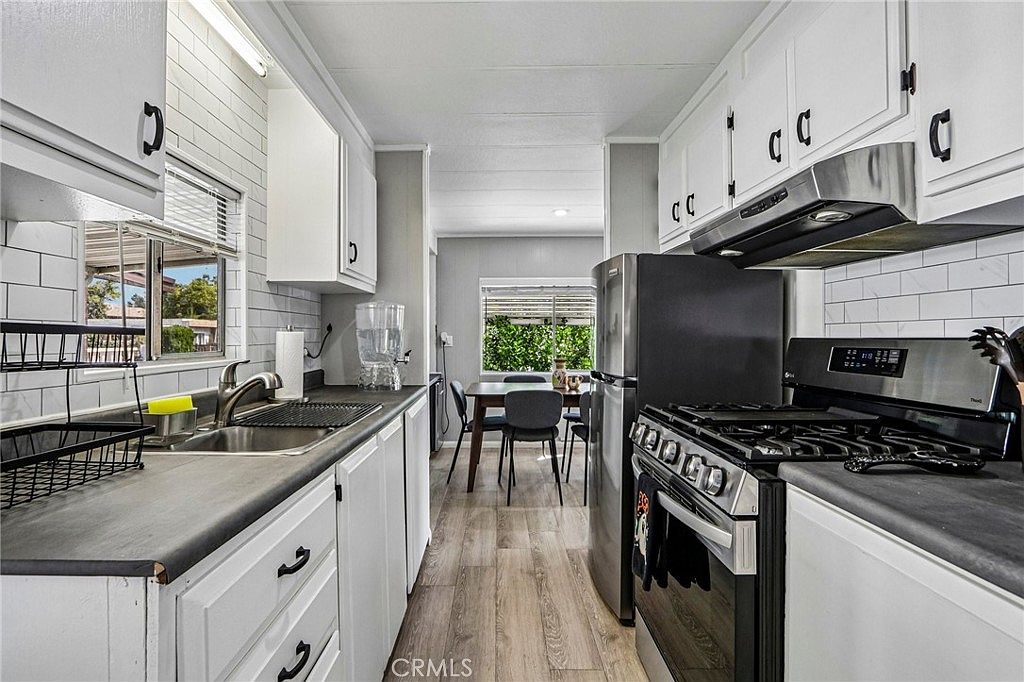 Updated galley kitchen with white cabinets and gas range