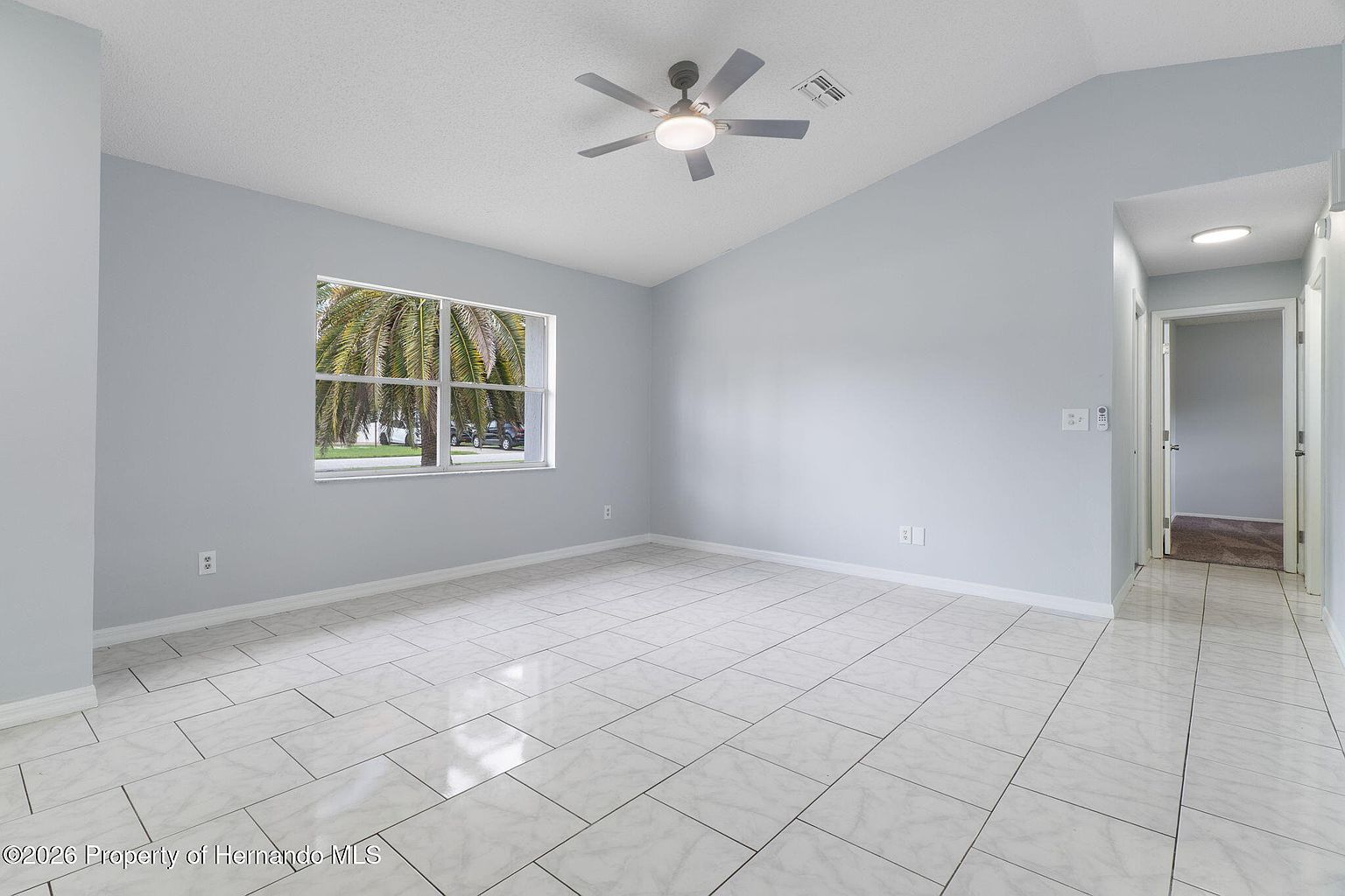 Bright open living room with vaulted ceiling and tile flooring