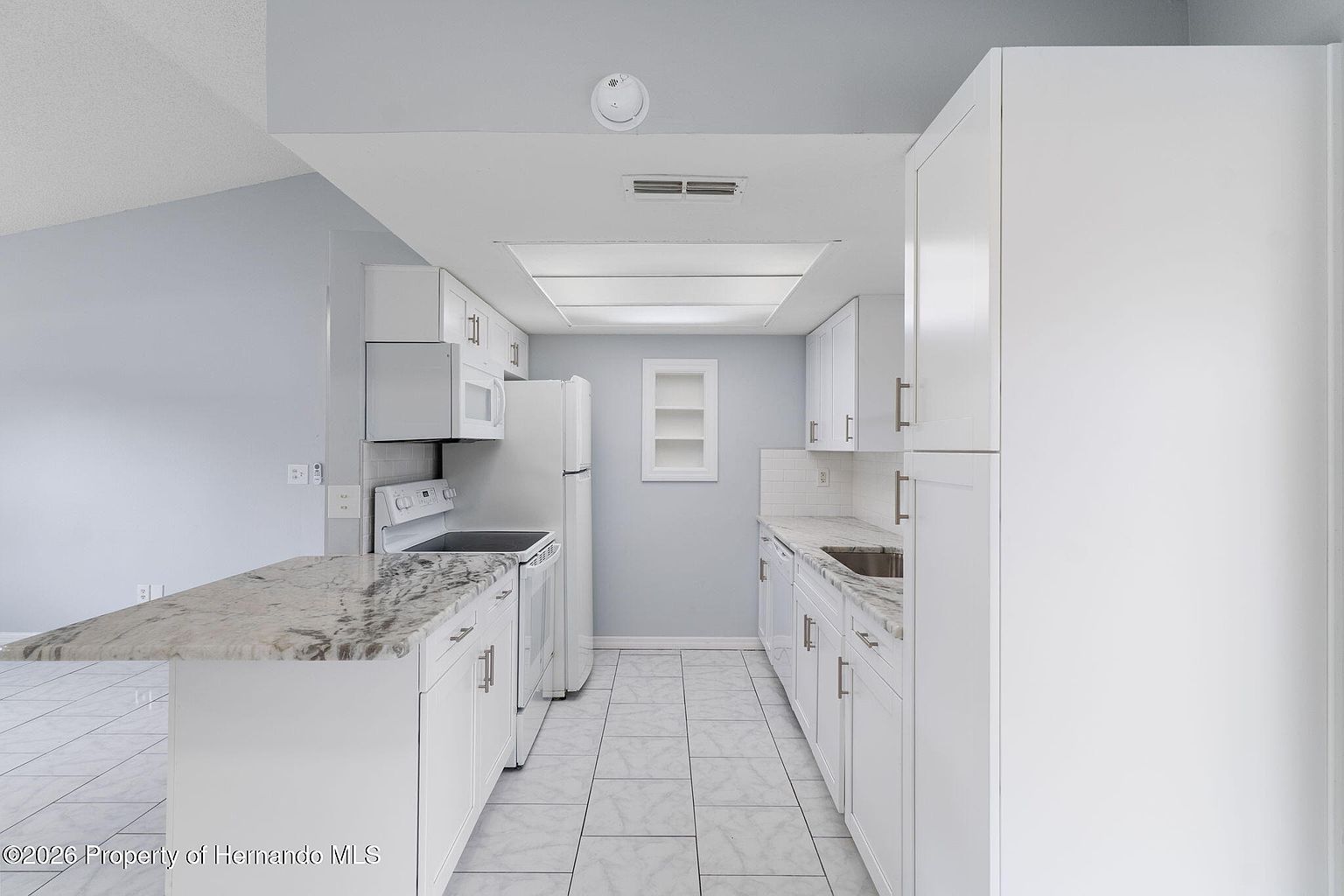 Updated white kitchen with stone-look counters and breakfast bar