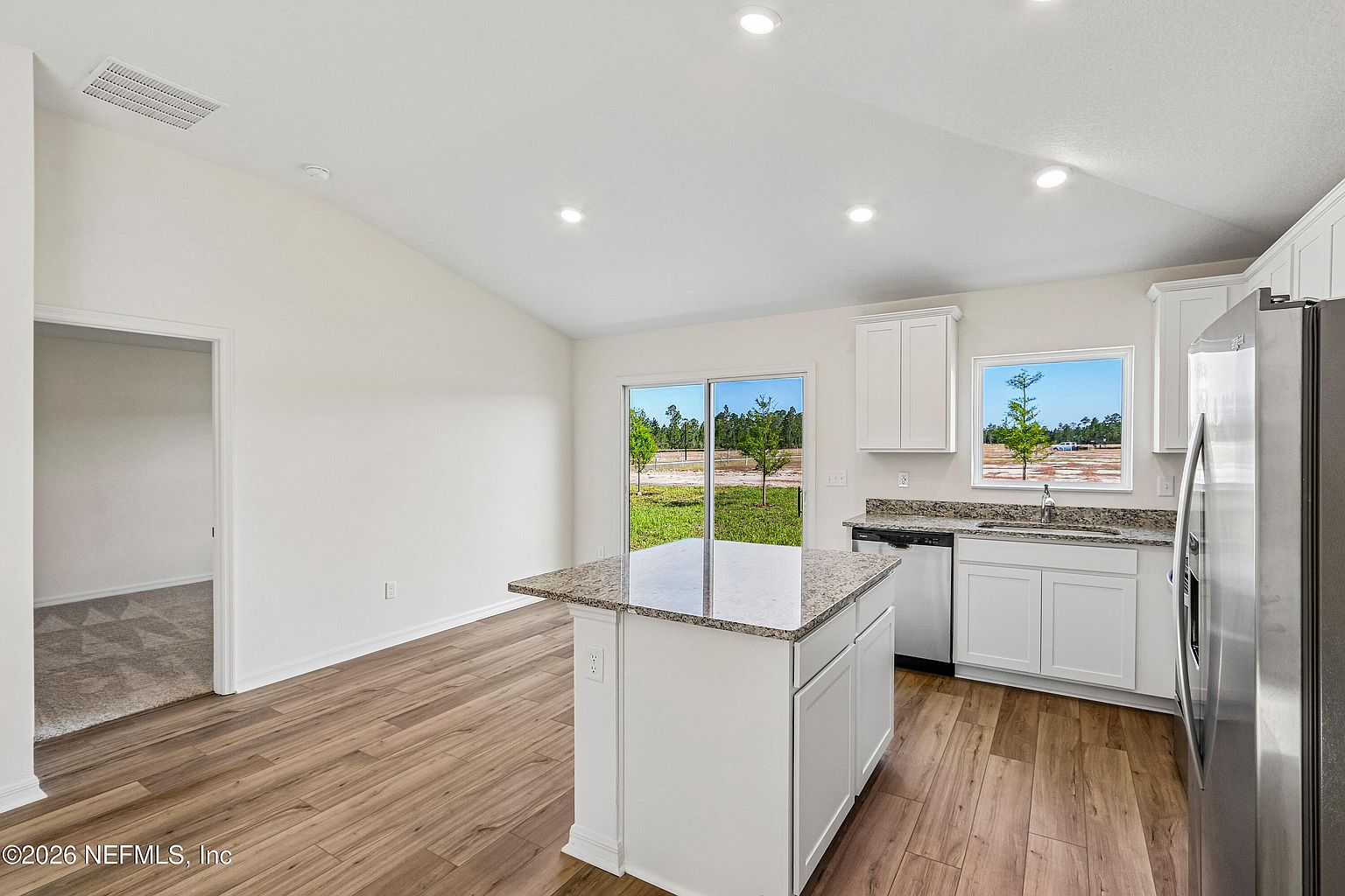 Bright kitchen with island, stone-look counters, and stainless appliances